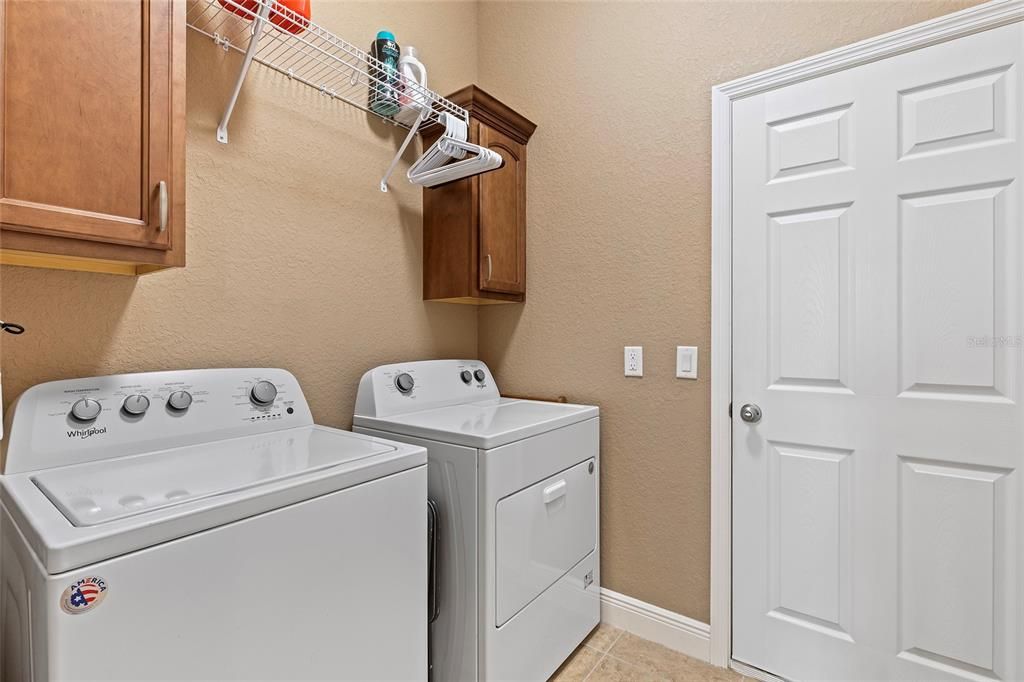 Laundry room with overhead cabinets, door leads to garage