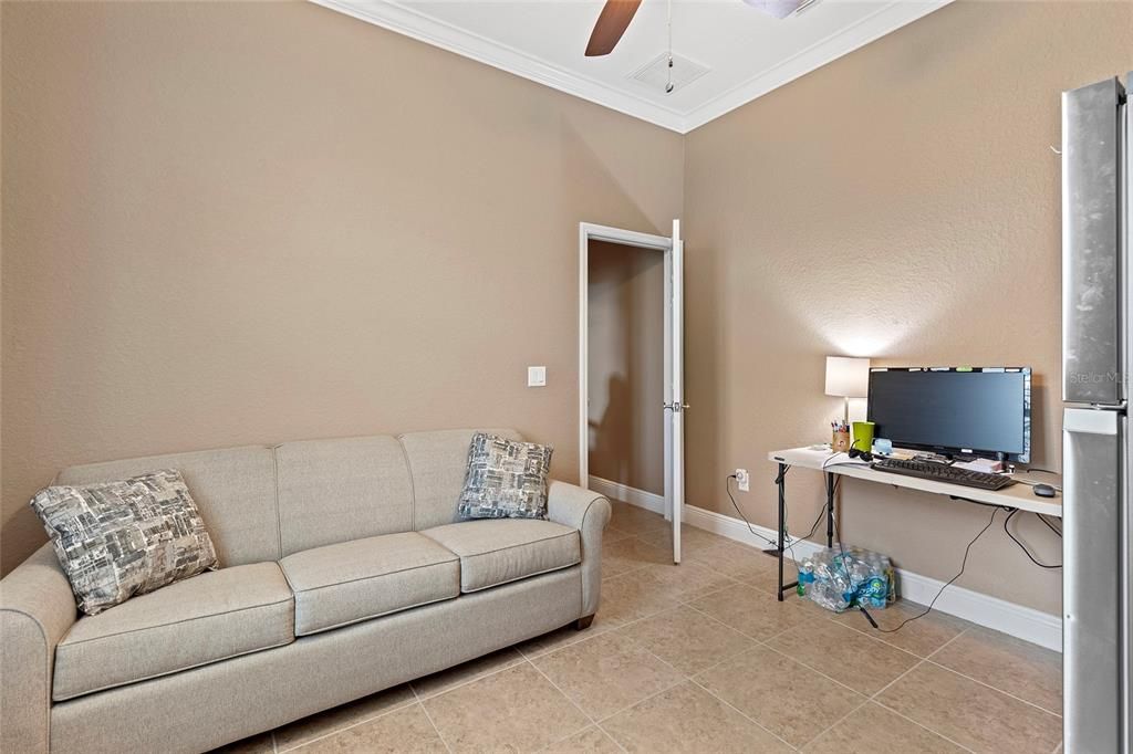 Guest bedroom with tile floor, currently used as office with sofa bed