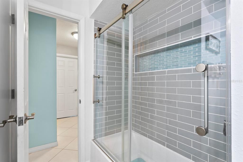 Custom glass shower door and beautiful tiles around the bath tub