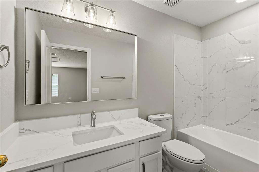 Fully remodeled upstairs bath with quartz vanity and tiled shower/tub combo