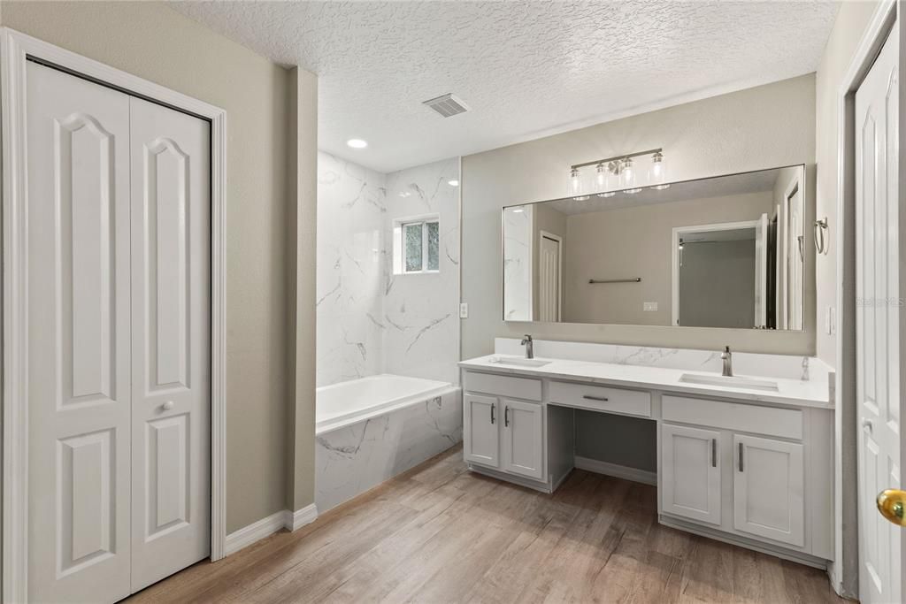 Master Bath features new LVP flooring, double quartz topped vanity, tile shower tub/combo and walk in closet