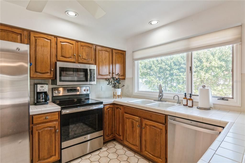 Tile countertops, stainless steel appliances and walnut cabinets.