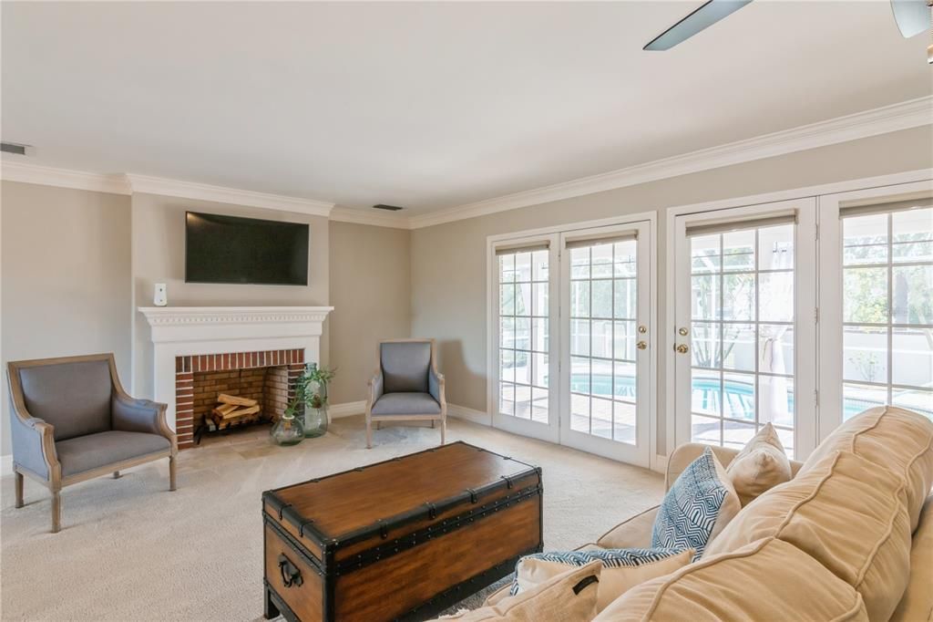 Living room with fireplace and French doors to pool area.