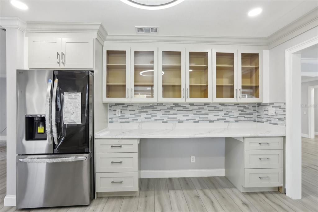 Kitchen with Deluxe French Door Refrigerator. Snack bar with glass front cabinets above.