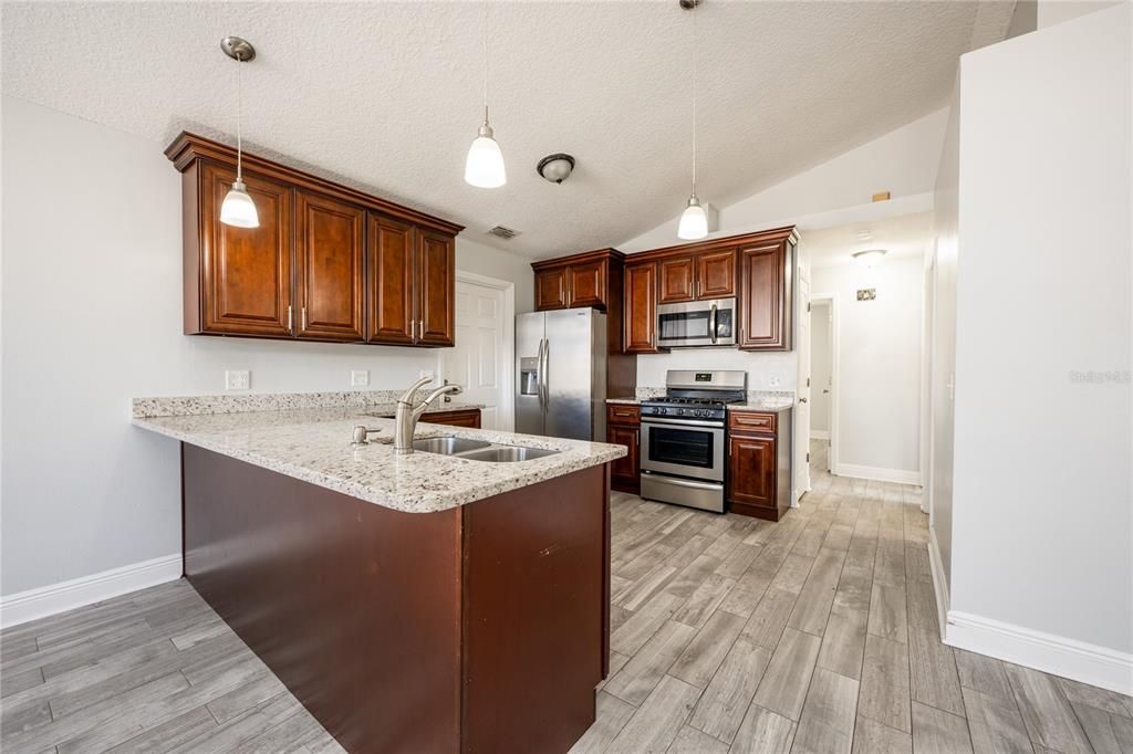 The home chef will delight in the updated kitchen featuring rich cabinetry, GRANITE COUNTERTOPS, a breakfast bar under pendant lighting, STAINLESS STEEL APPLIANCES (that include a GAS STOVE!) and a pantry for ample storage.