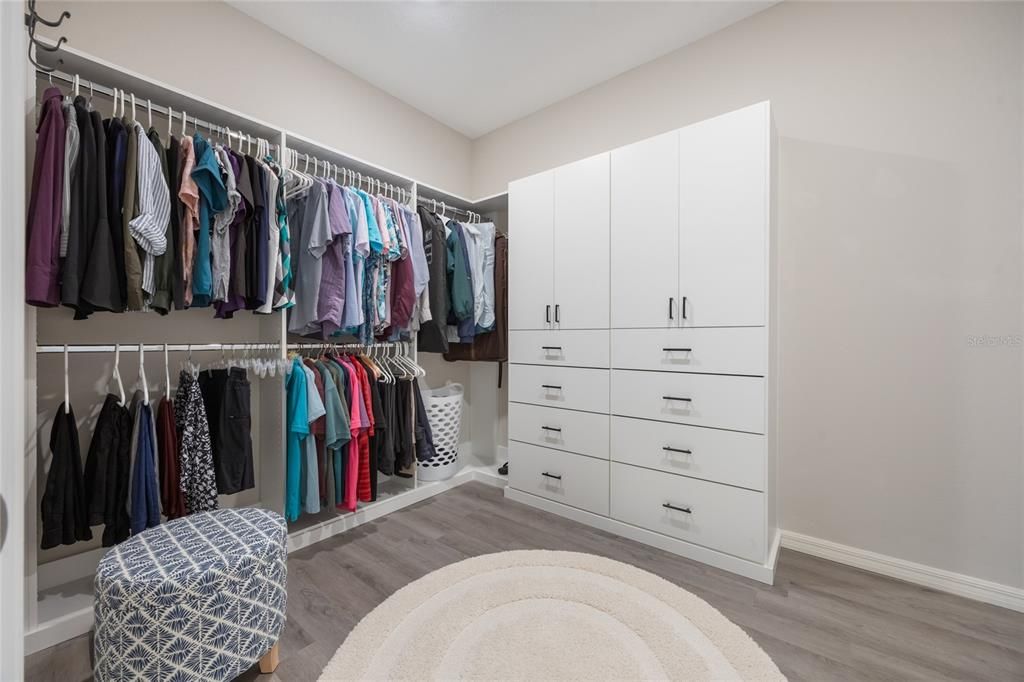 Huge walk in closet in the primary suite offers built in cabinetry.