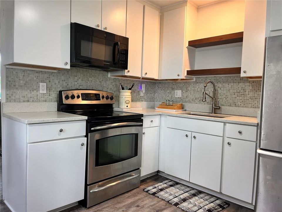 Kitchen with range, microwave, refrigerator, SS sink, quartz counters, new cabinets in 2021