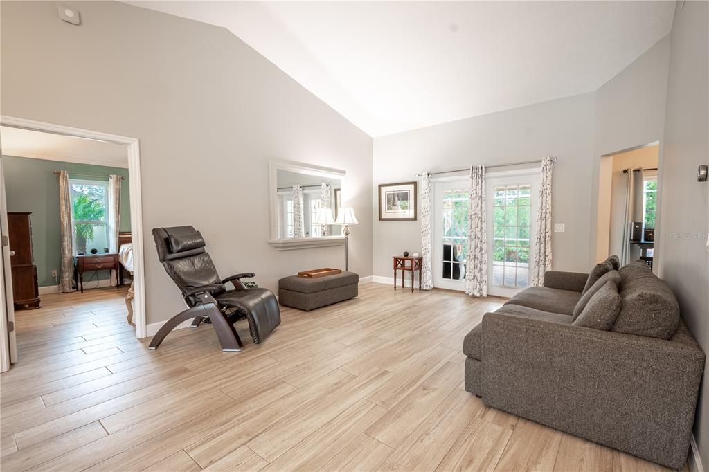 The spacious living room features a vaulted ceiling and French doors that lead to the screened in lanai and private backyard.