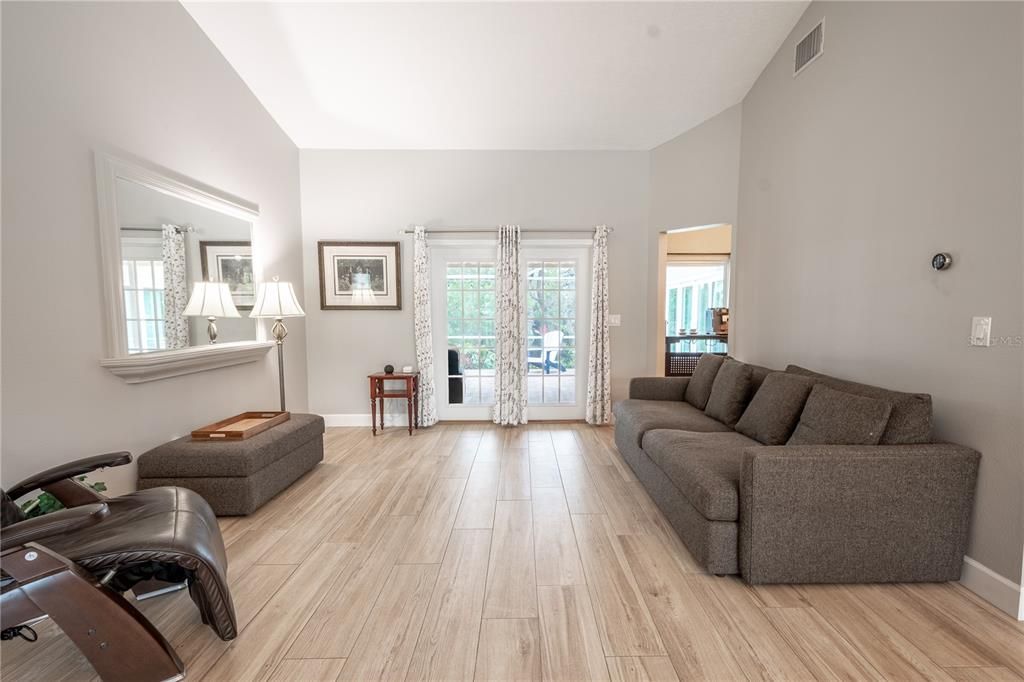 The living room has wood-look porcelain tile and neutral tone walls.