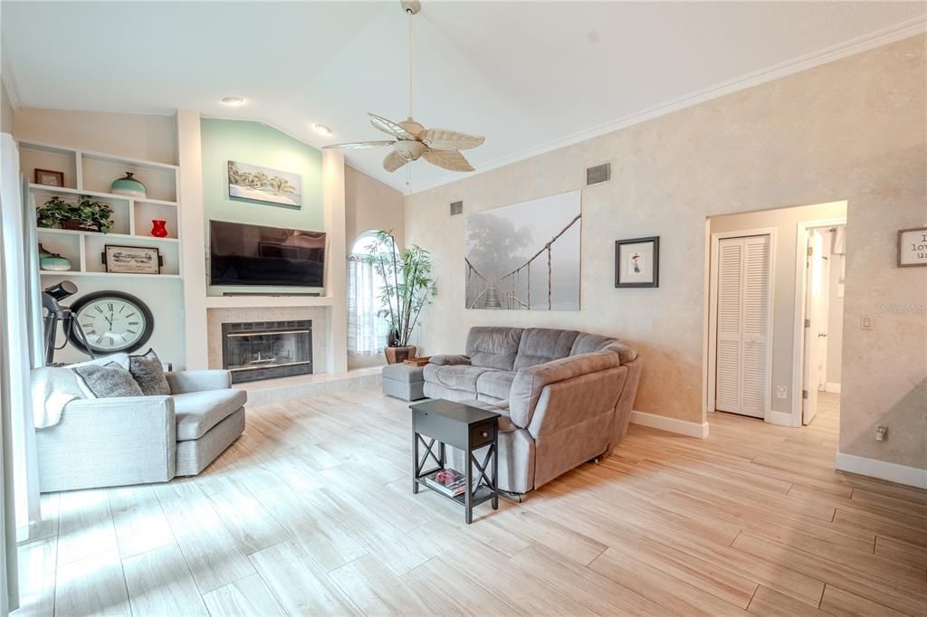 The light and bright family room features a wood burning fireplace with built-in shelving.