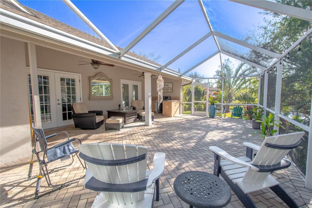 The partially covered, screened in lanai, brick-pavered lanai has a high screen for a light and airy feel.