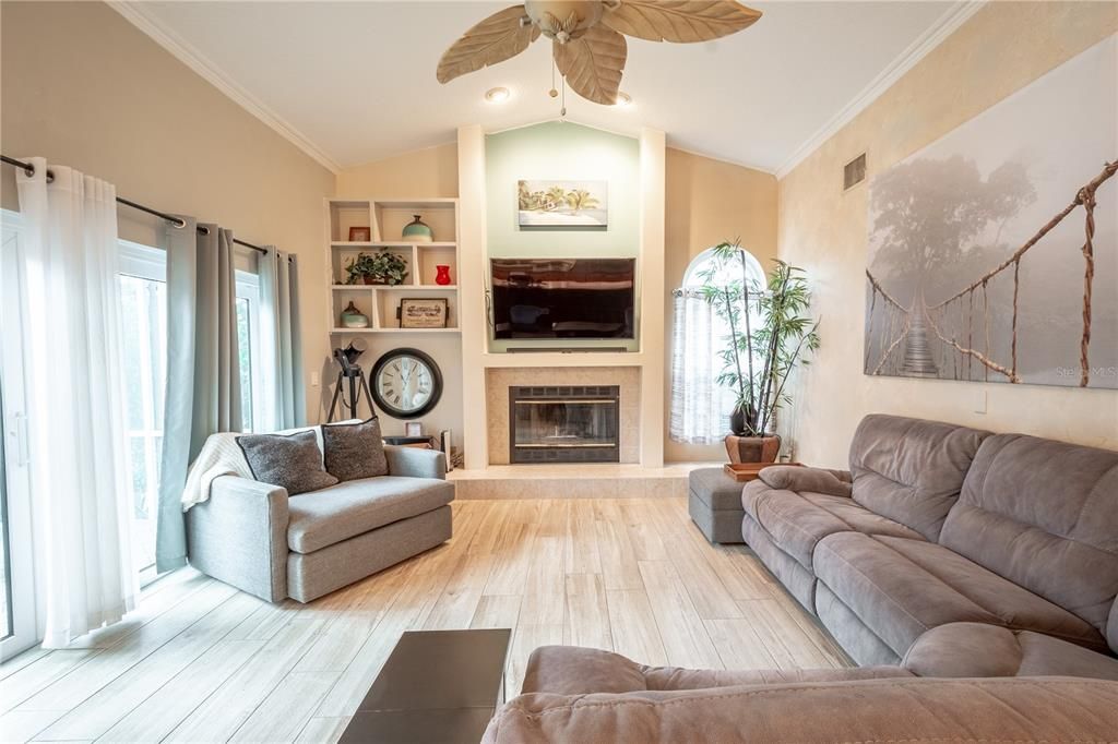 The family room has wood look porcelain tile, high ceilings, a ceiling fan and hurricane impact sliding glass doors to the private lanai.