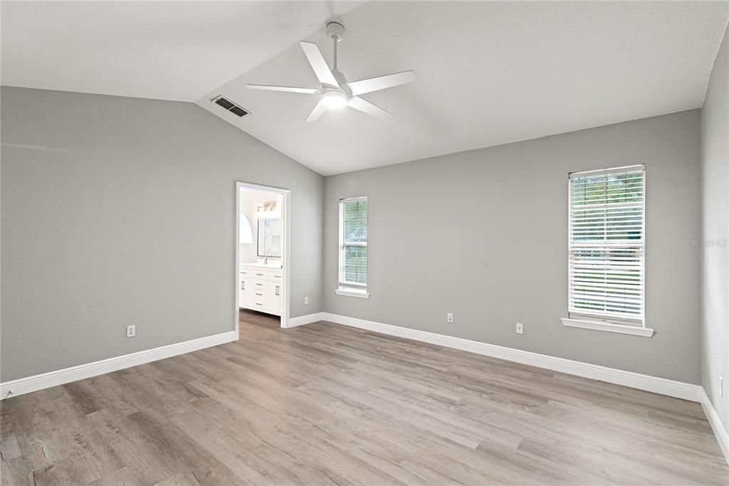 Master Bedroom features new LVP flooring, vaulted ceilings and entry to enclosed and covered rear patio.