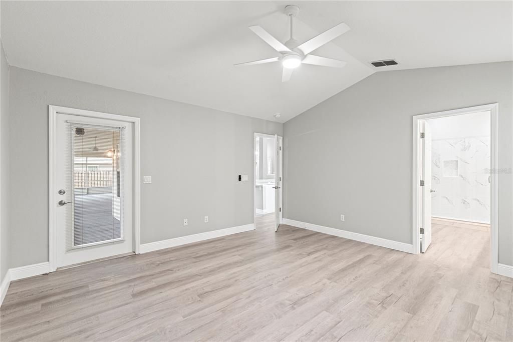 Master Bedroom features new LVP flooring, vaulted ceilings and entry to enclosed and covered rear patio.