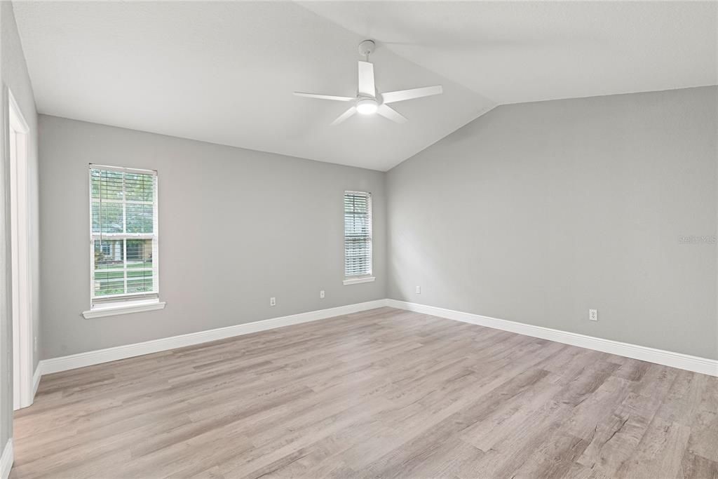 Master Bedroom features new LVP flooring, vaulted ceilings and entry to enclosed and covered rear patio.