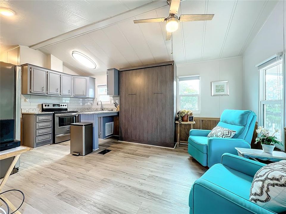 Another view of the kitchen, wall bed, and great room.