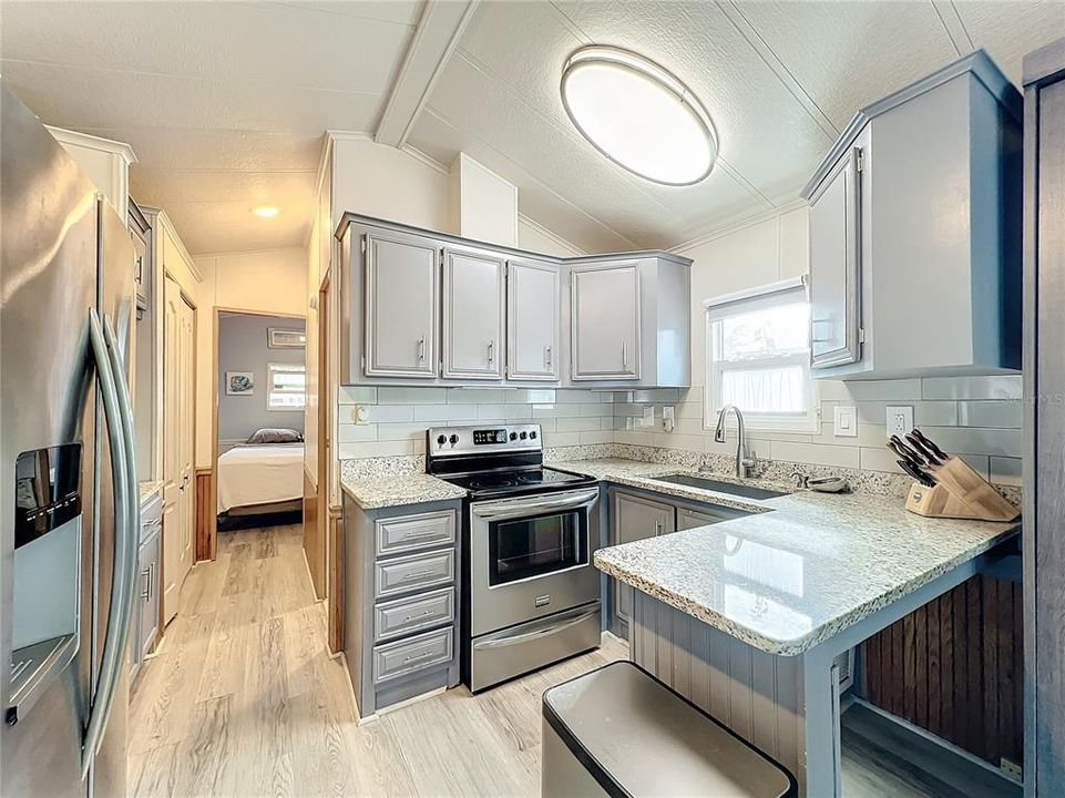 Kitchen beautifully updated with granite counters, stainless steel appliances, gray cabinets, and new faucet.