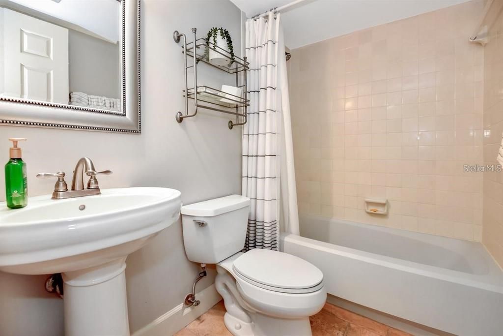 Charming and updated bathroom featuring modern fixtures, travertine flooring, and coastal-inspired decor for a spa-like retreat