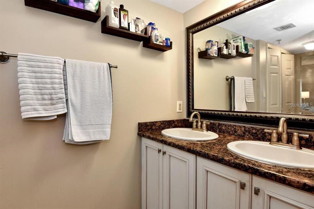 Charming and updated bathroom featuring modern fixtures, travertine flooring, and coastal-inspired decor for a spa-like retreat.