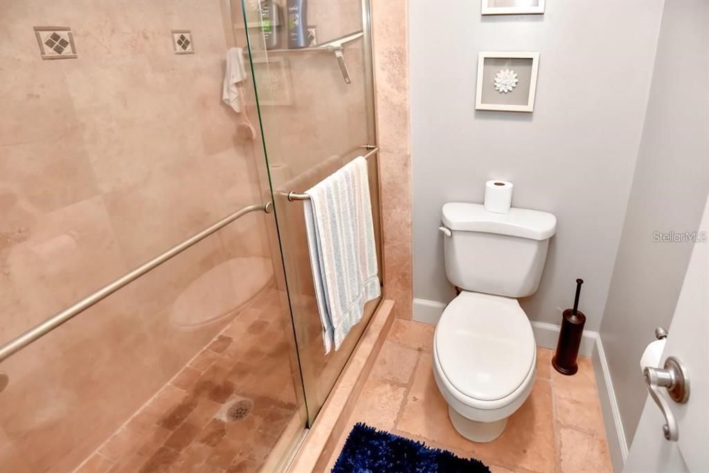 Charming and updated bathroom featuring modern fixtures, travertine flooring, and coastal-inspired decor for a spa-like retreat.