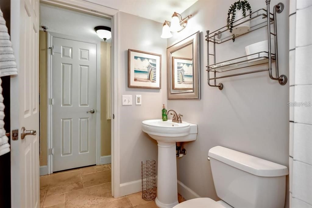 Charming and updated bathroom featuring modern fixtures, travertine flooring, and coastal-inspired decor for a spa-like retreat.