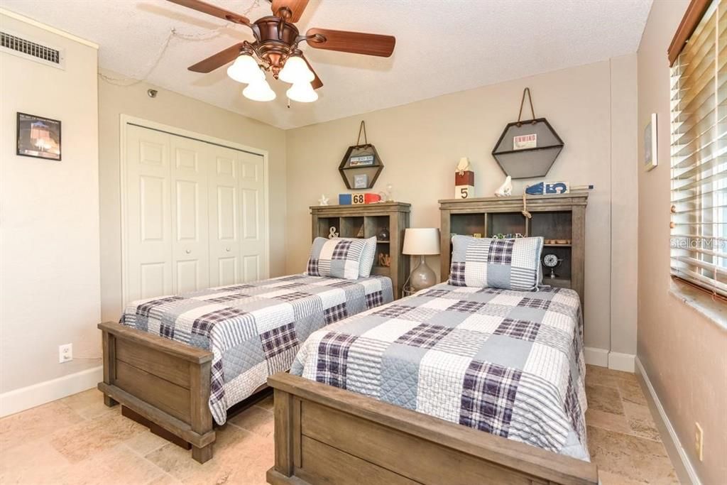 Bright and inviting guest bedroom featuring twin beds, charming decor, and ample closet space for ultimate comfort.