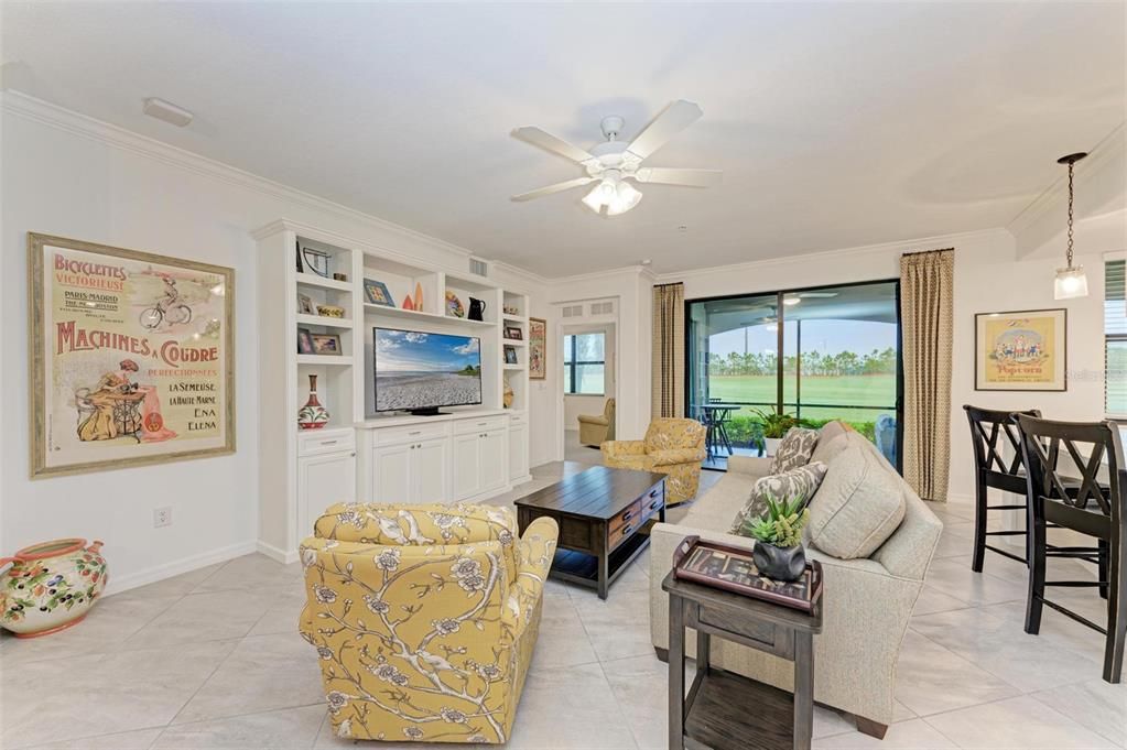 Living room features a $16,000 custom built entertainment center with a tinted sliding door to the spacious lanai and Primary Bedroom just beyond to the left of photo