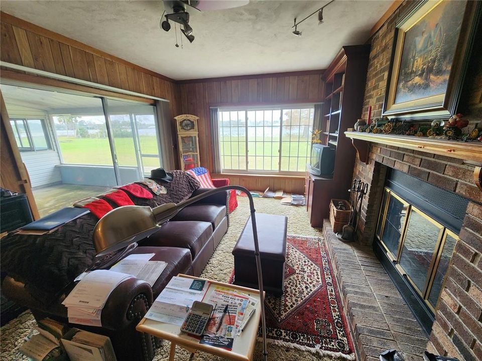 Rear family room. Screened patio at left and woodburning fireplace at right.