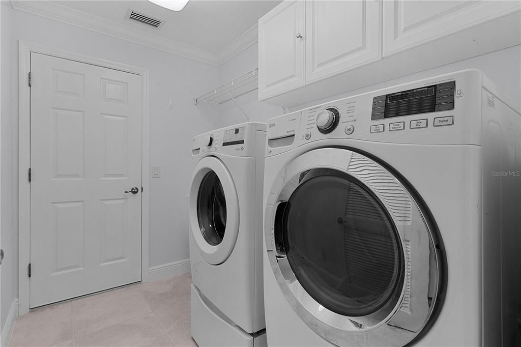 LAUDRY ROOM WITH GAS DRYER AND WAHSER.  CABINTRY OVERHEAD, AND UTILITY SINK.  ENTRY TO THE GARAGE