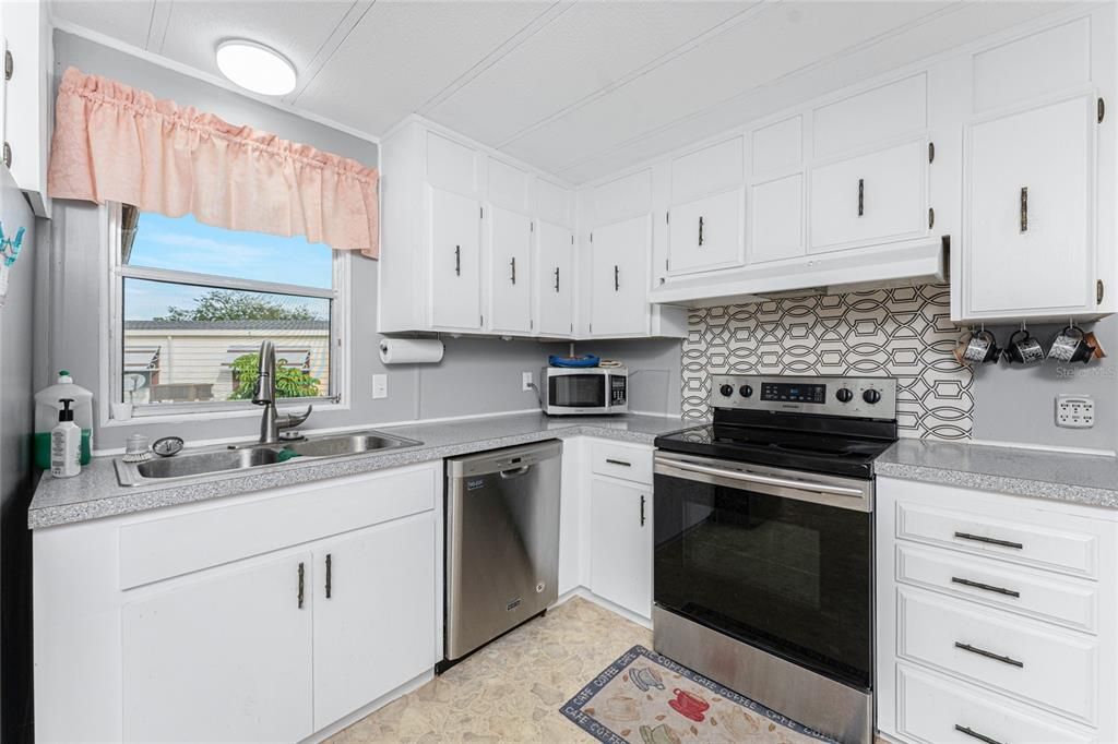 The kitchen has a window for natural light, plenty of cabinets and nice backsplash behind the stove.