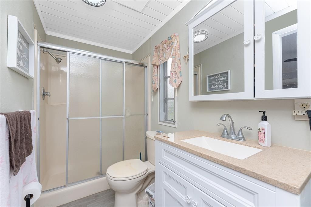 The master bathroom has a step in shower, updated mirror and light fixture and nice vanity with solid surface countertop.