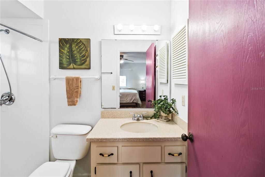 Main bathroom with solid countertops, shower and closet pantry behind the door.