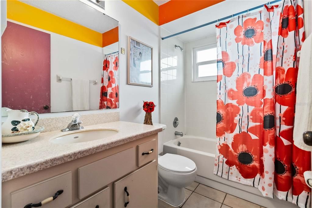 Hall bathroom with tub shower combo and solid countertops