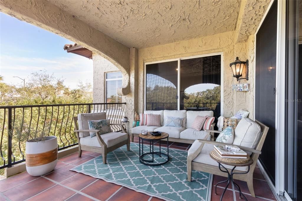 Large covered balcony with 2 sets of sliders from living room and primary bedroom