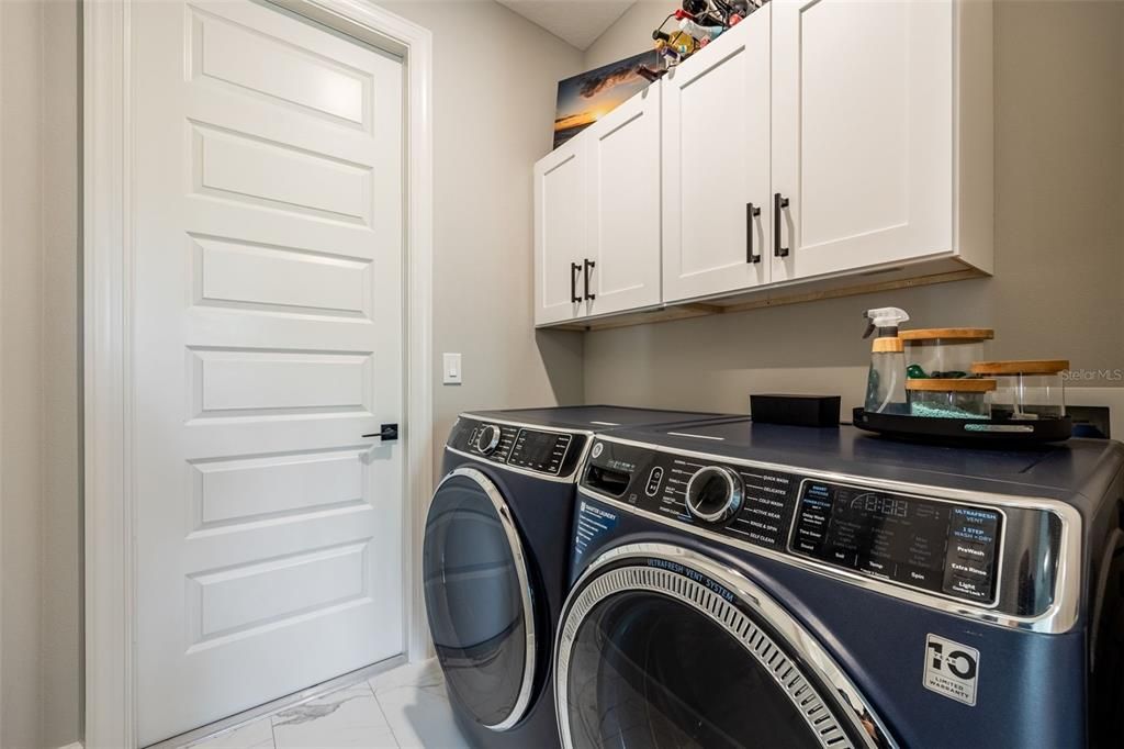 Laundry room, tile flooring, storage cabinets added. Door leads to 3 car garage