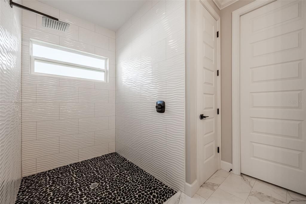 Beautifully tiled shower floor to ceiling with rainfall shower head.