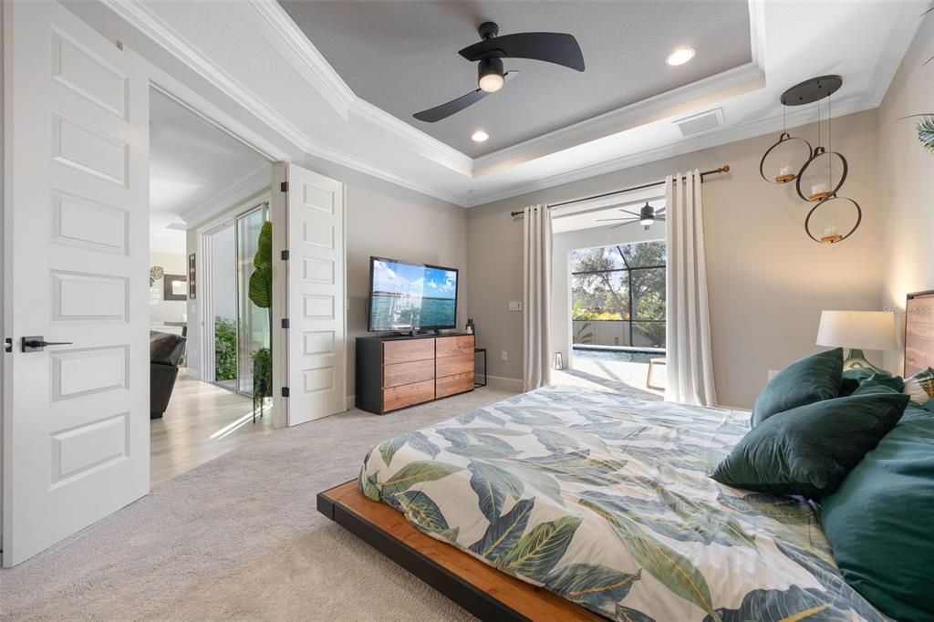 Primary bedroom has upgraded carpet, pocket siiding doors for private access to Lanai and Pool. A tray ceiling was added to give extra height in this woom, and double doors access from living area.