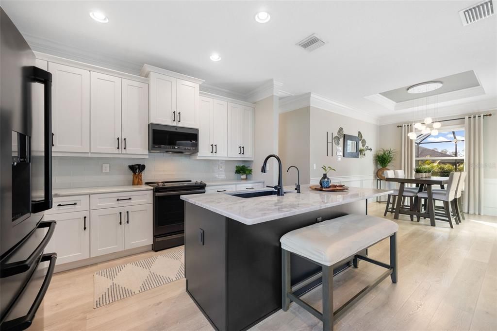 Kitchen opens to designated Dining Space featuring a Beautiful Light Fixture, decorative Wainscoating paneling, Tray Ceiling.