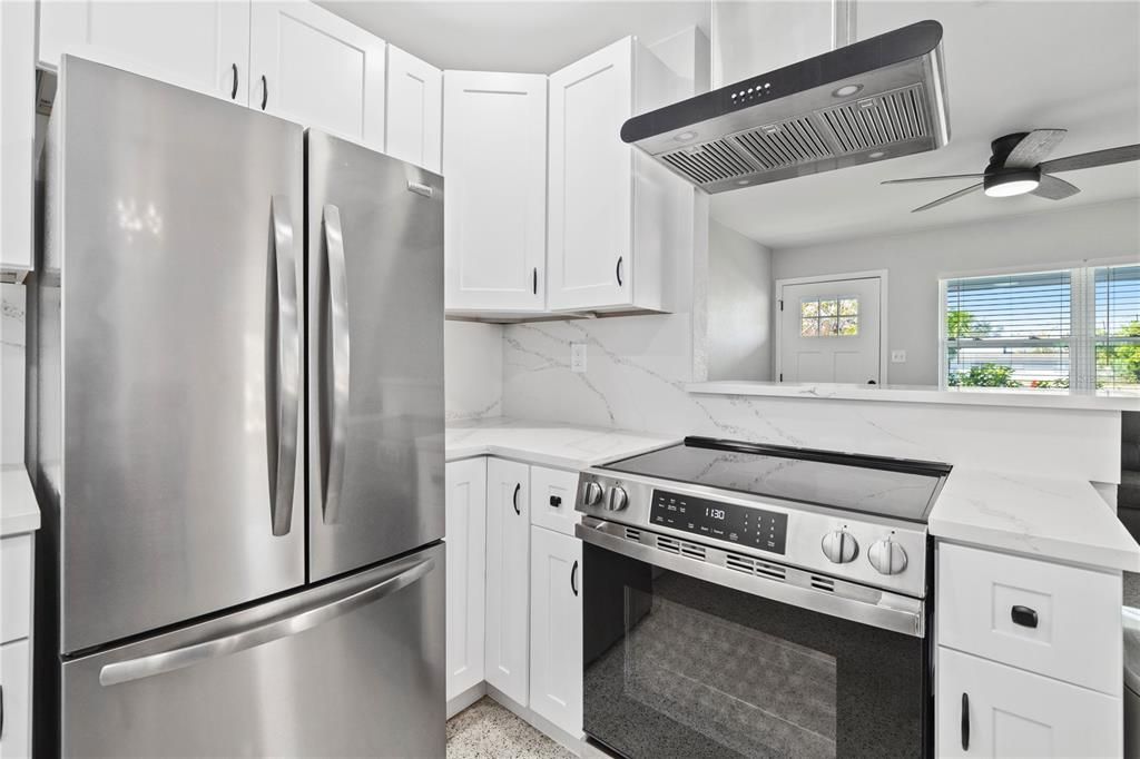 New kitchen with French door refrigerator and stove hood.