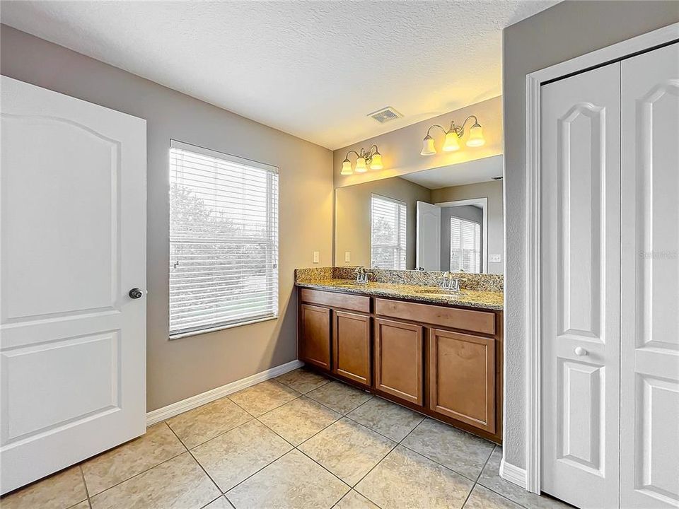 The bathroom ensuite has dual sinks and a linen closet.