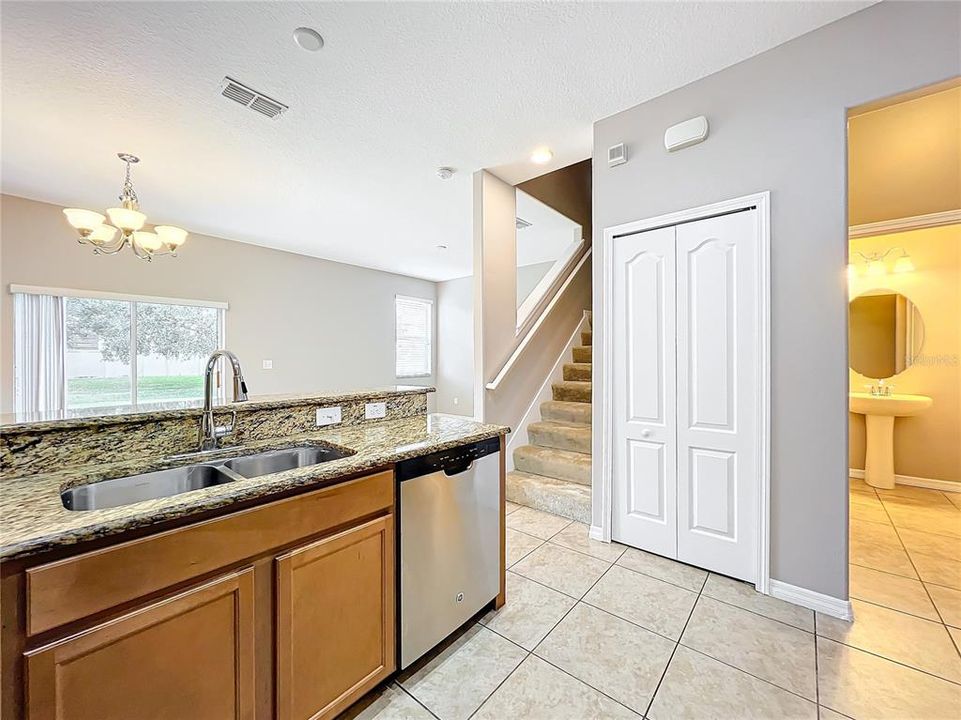 A view of the breakfast bar looking toward the guest bathroom, staircase, and family room area.