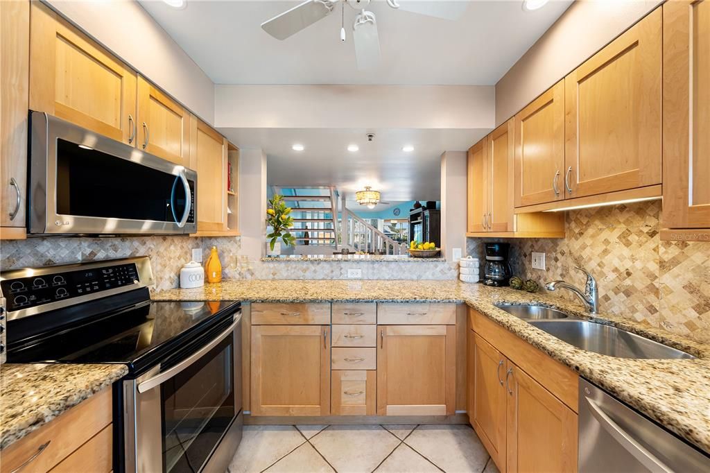 Kitchen features granite counter tops, tile backsplash, newer stainless steel appliances, and pass-through to breakfast bar.