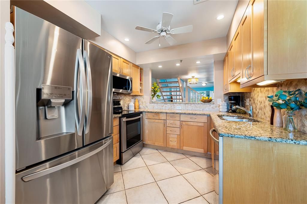 Kitchen features granite counter tops, tile backsplash, newer stainless steel appliances, and pass-through to breakfast bar.