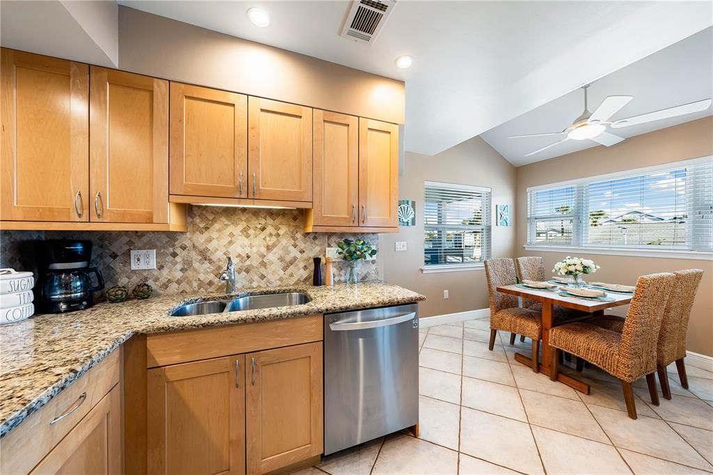 Kitchen features granite counter tops, tile backsplash, newer stainless steel appliances, and pass-through to breakfast bar.