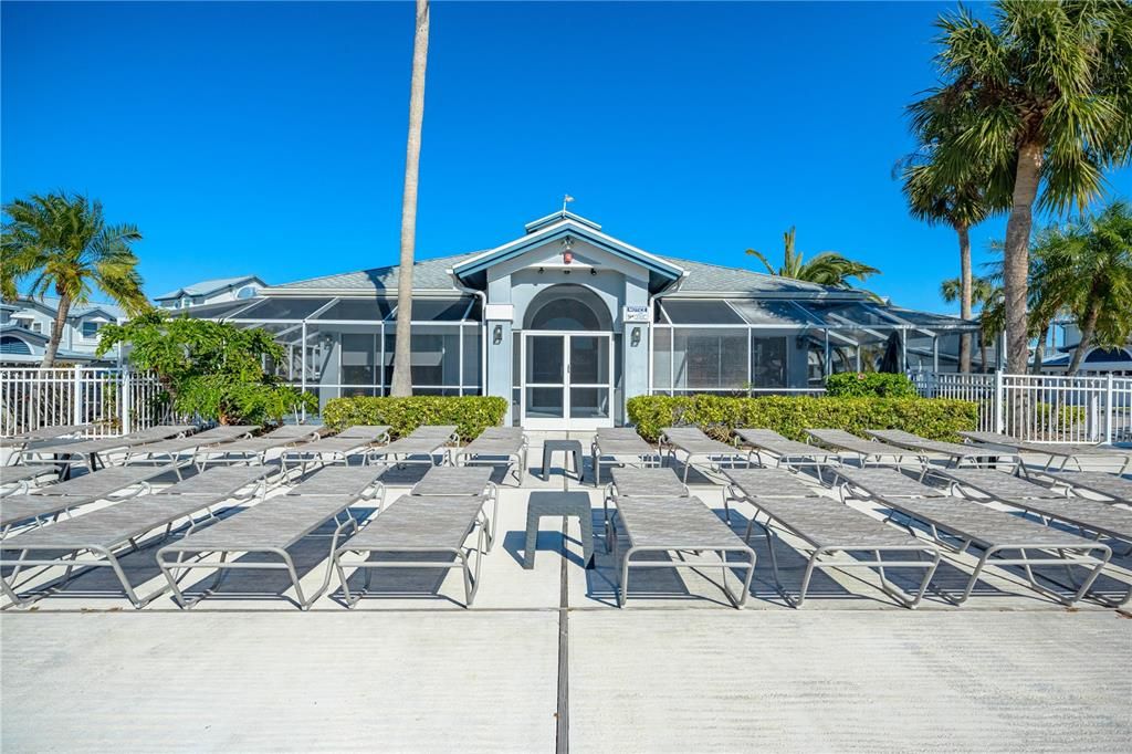 Pool-side lounge chairs and clubhouse featuring fitness room and sauna.