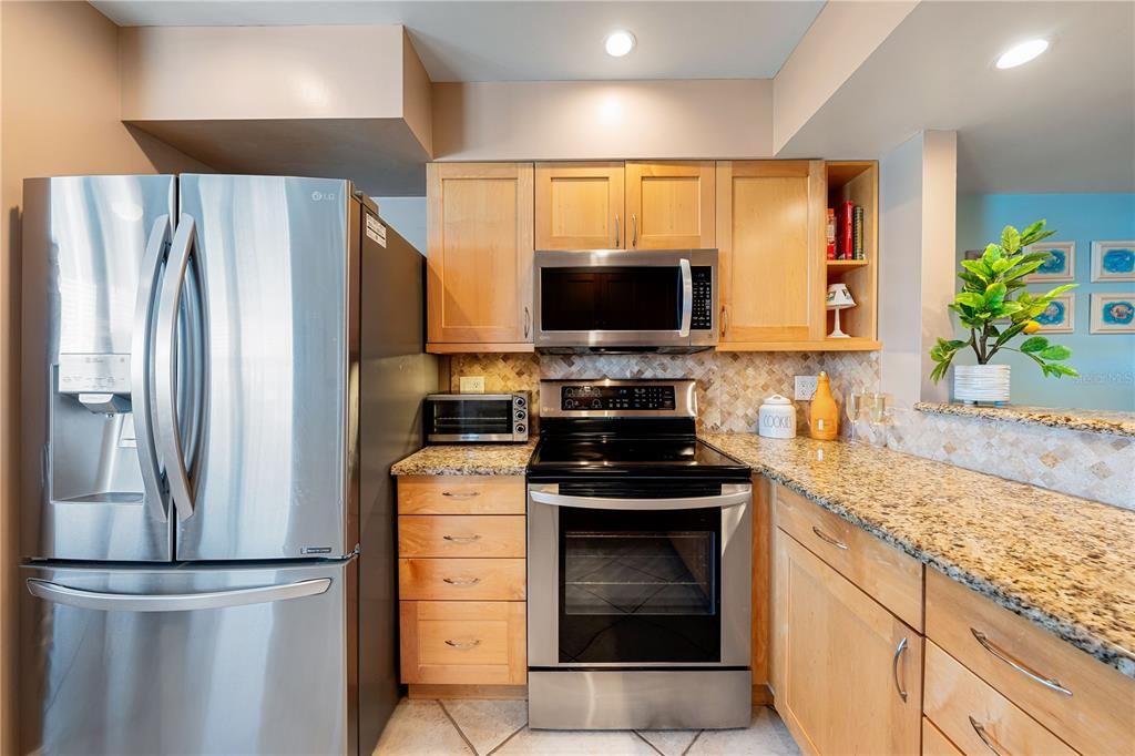 Kitchen features granite counter tops, tile backsplash, newer stainless steel appliances, and pass-through to breakfast bar.