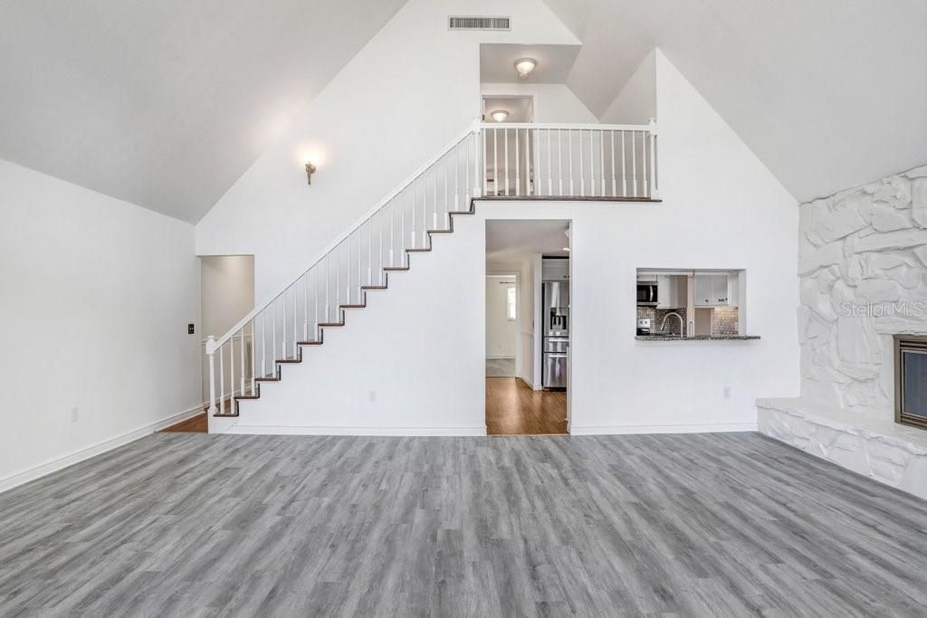 Living Room with pass through to kitchen, staircase to primary suite and wood burning fireplace.