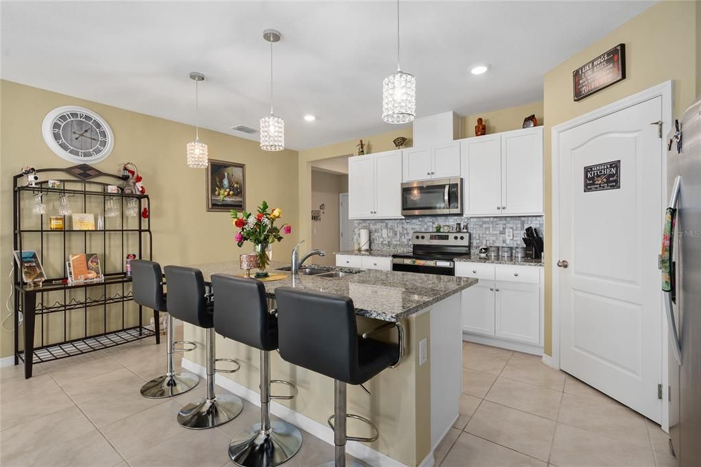 BEAUTIFUL KITCHEN WITH LARGE ISLAND, GRANITE COUNTERTOPS, CUSTOM BACKSPLASH AND MODERN WHITE CABINETS WITH STAINLESS STEEL APPLIANCES.