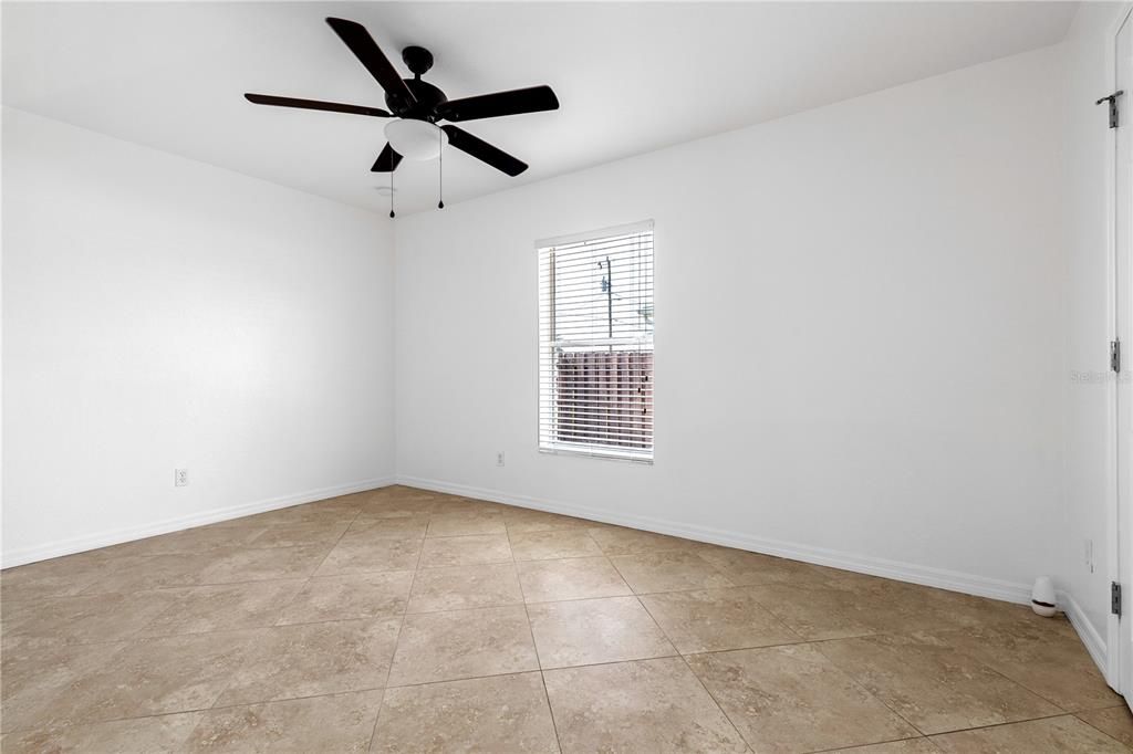 Middle large bedroom with ceiling fan and tile flooring and large closet