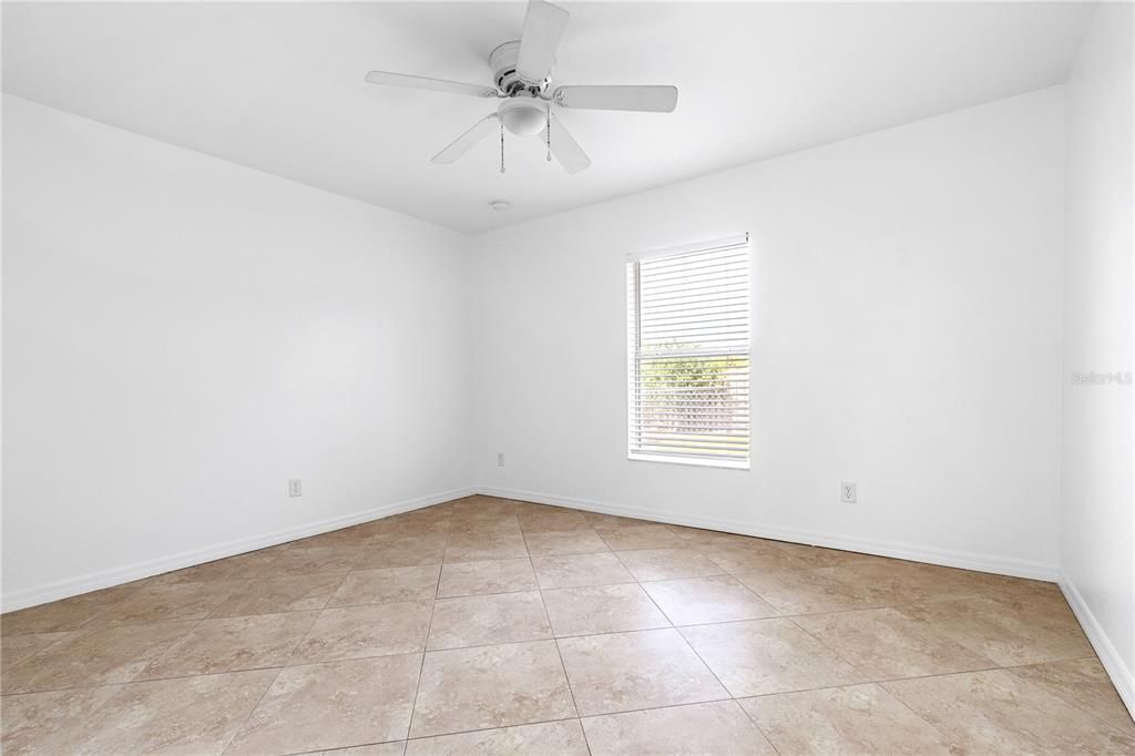 Back large bedroom with ceiling fan and tile flooring and large closet